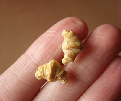 Hand holding a couple of mini croissants about the size of peas. They're so little!
